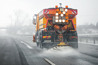 Streumaschine für Winterdienst auf eisbedeckter Autobahn